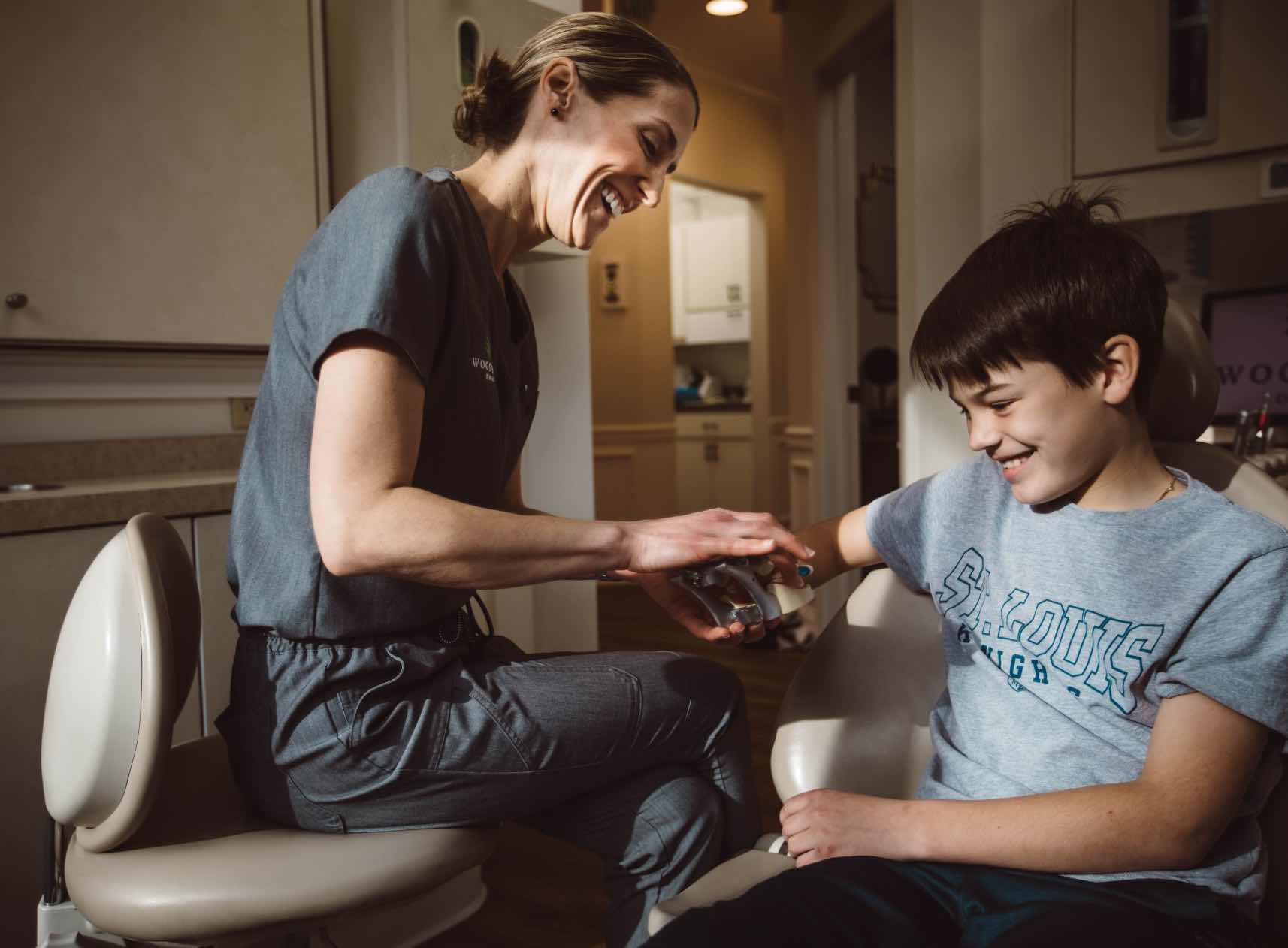Photo of a dental team member showing a tooth model to a young patient