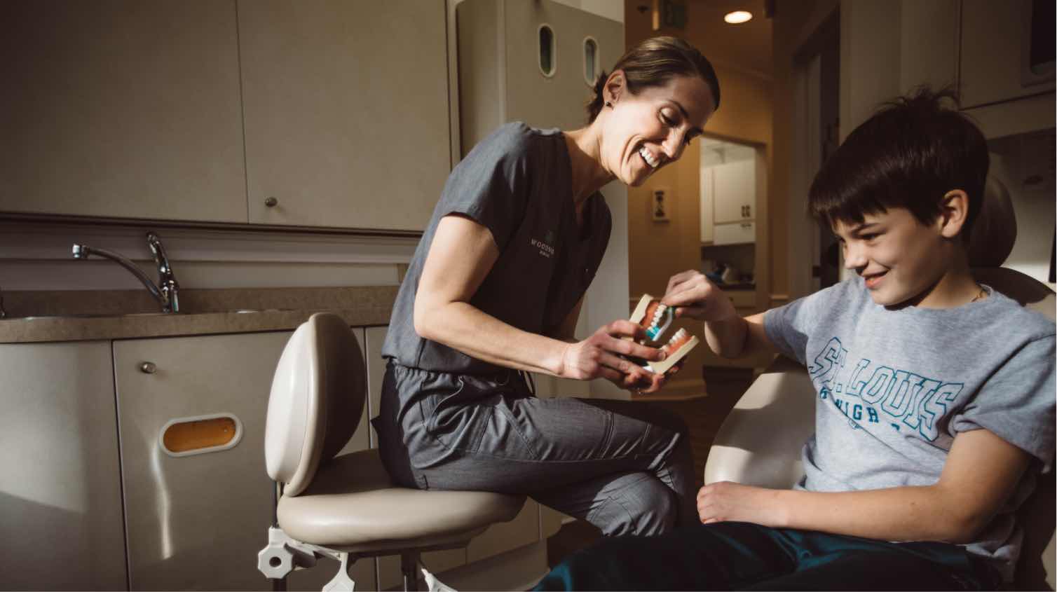 Photo of a Woodside hygienist with a young patient showing a dental model
